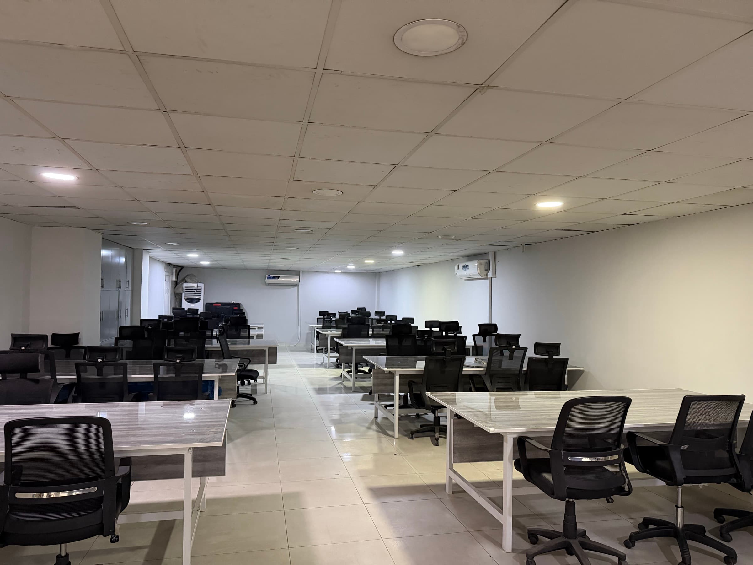 The open coworking floor at Coworking Space on Murree Road, Rawalpindi, with rows of desks and office chairs under ceiling lighting.