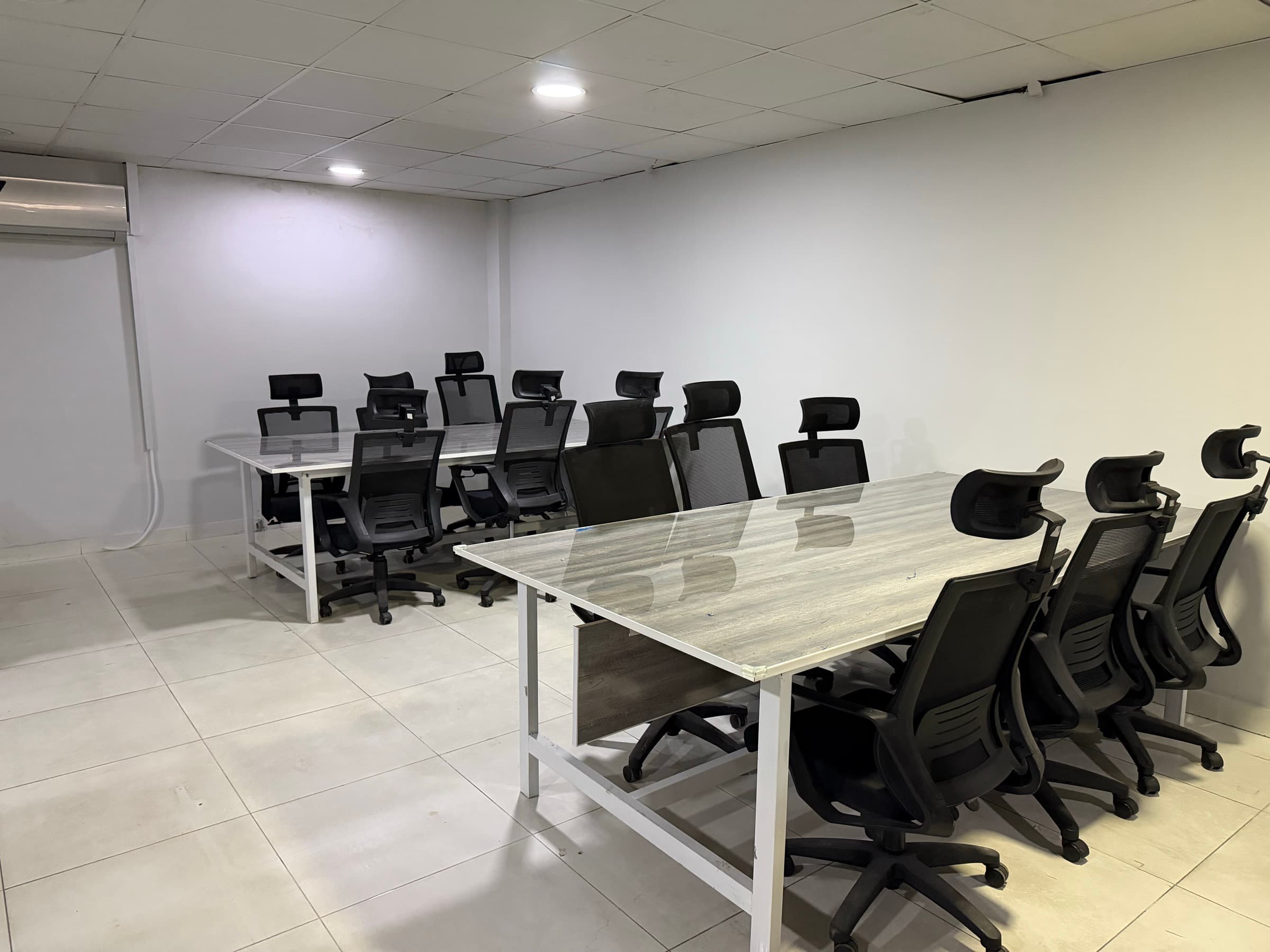 Two long desks set up for a team, with high-backed office chairs on both sides.